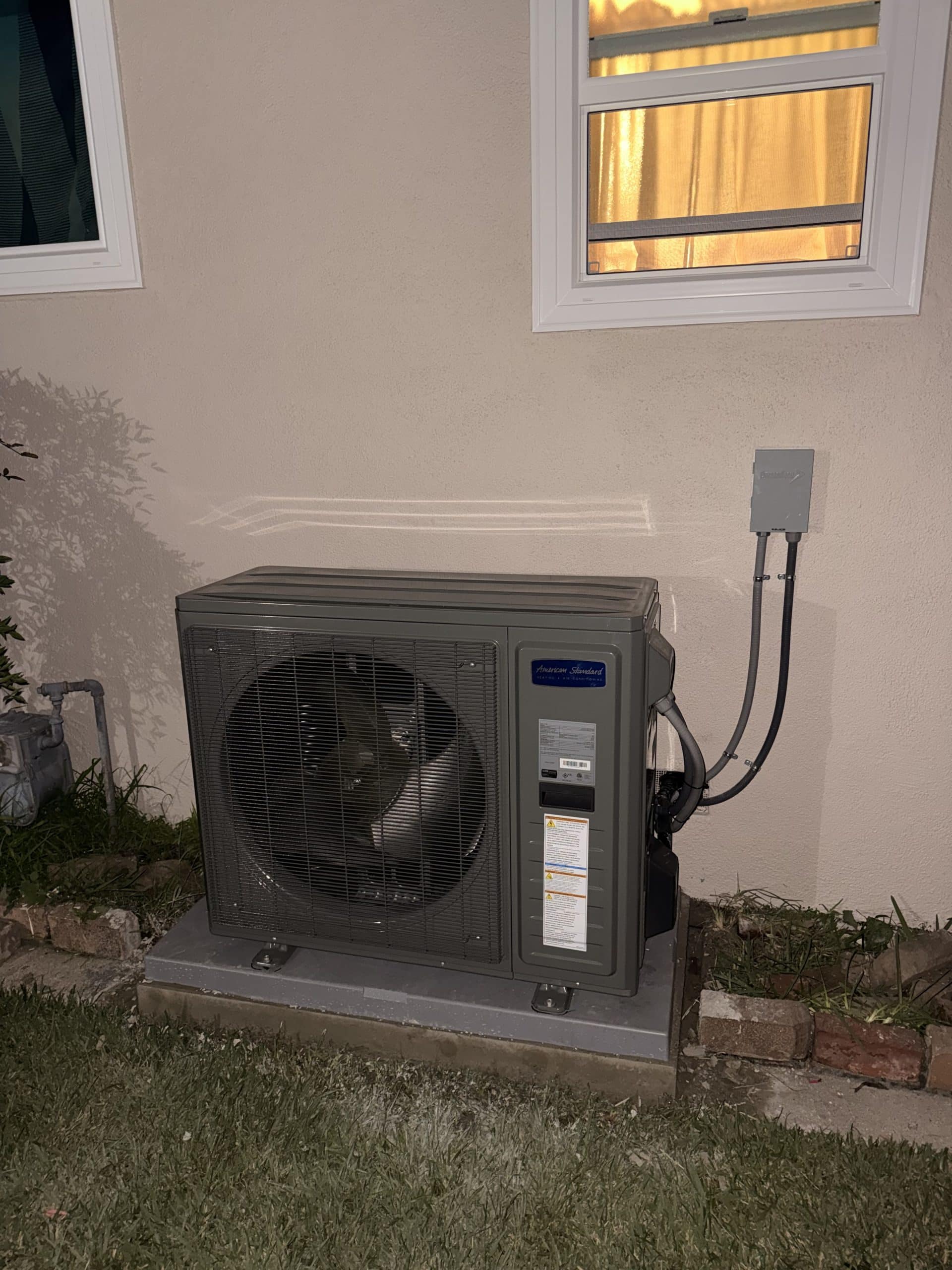 Outdoor air conditioning unit at night by window.