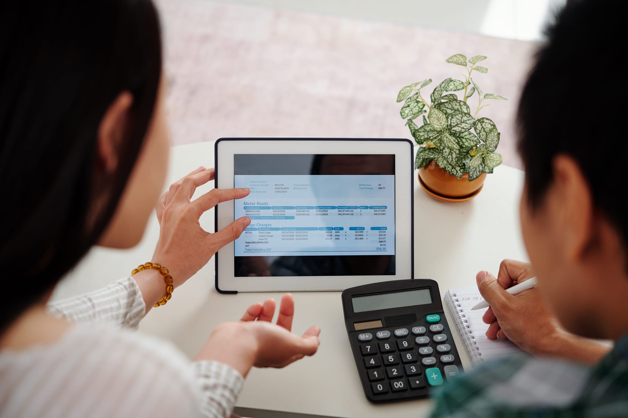 People reviewing bill on tablet with calculator