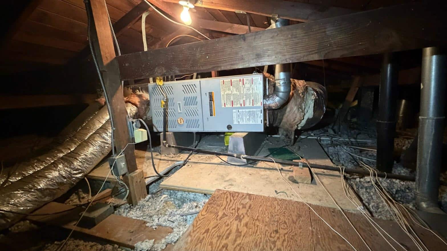 Gas furnace in cramped attic space with ductwork visible during HVAC change-out project in Norwalk