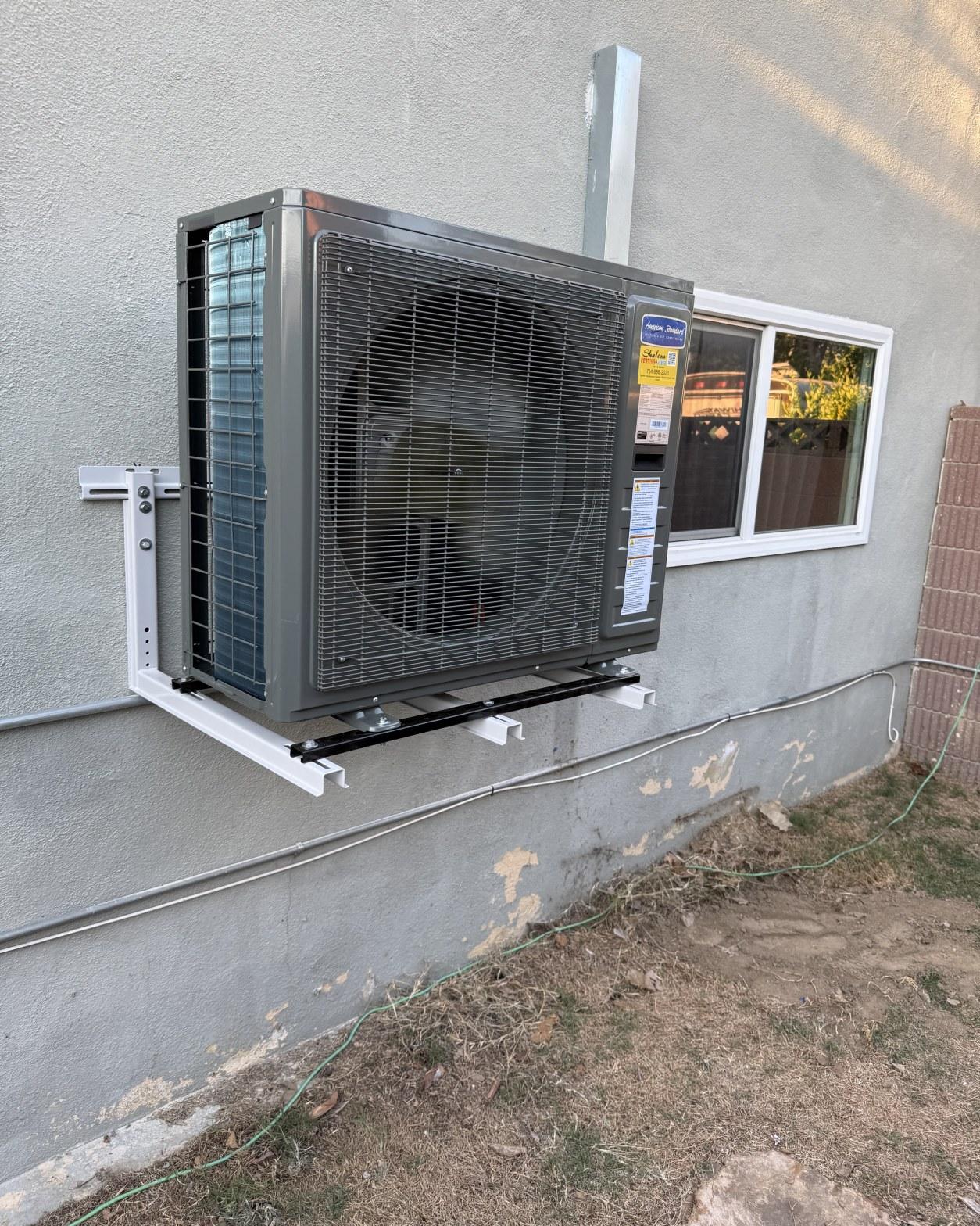 American Standard mini-split condenser unit wall-mounted on bracket system on stucco exterior, Carson CA