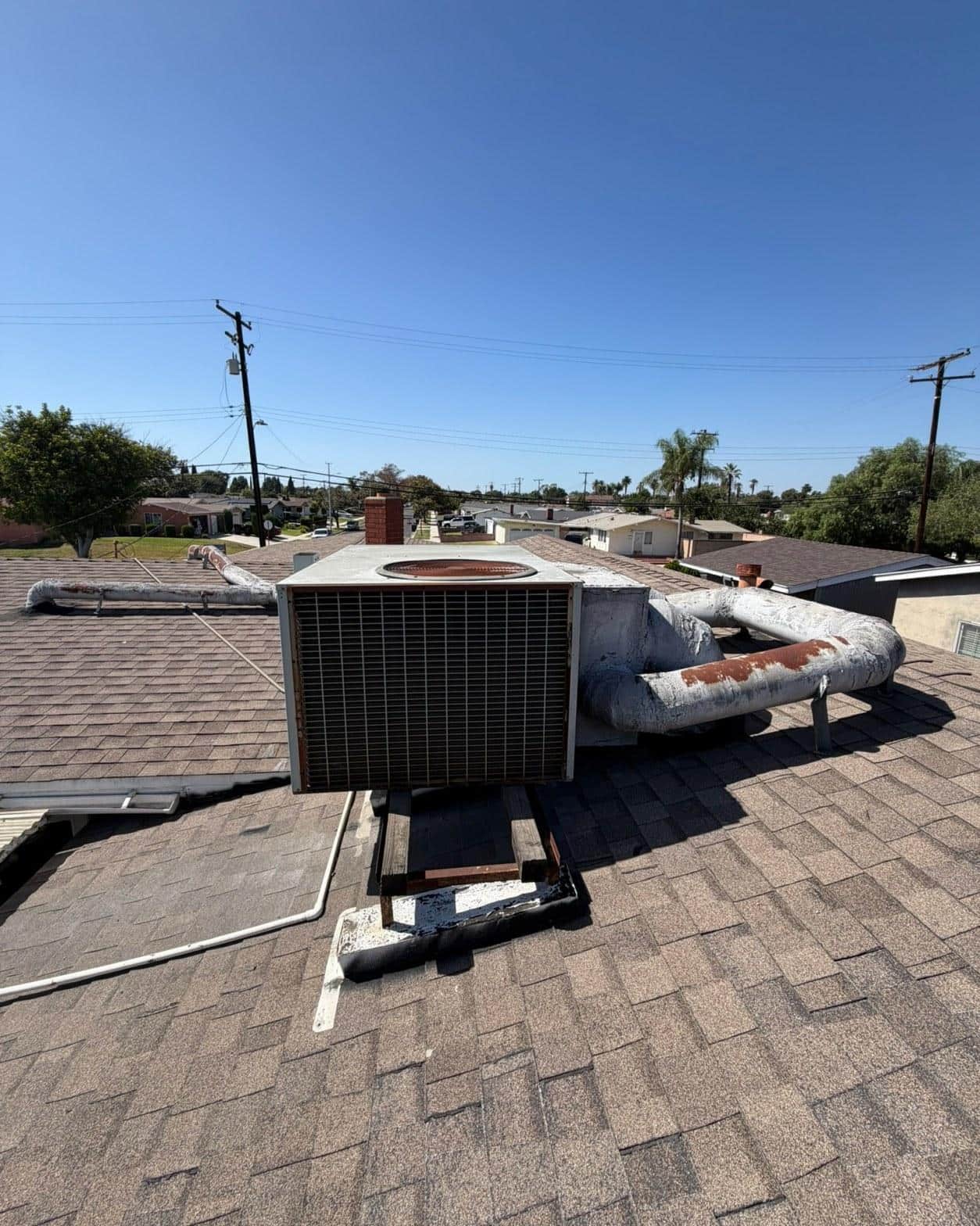 Old 4-ton rooftop AC package unit with rusted housing and deteriorating flex ducts on Norwalk home shingle roof